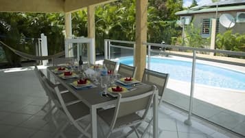 Enjoy meals al fresco with a view of the pool and lush surroundings.