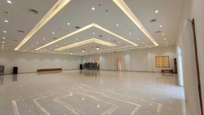A spacious, well-lit hall with a polished floor, recessed lighting, and a row of chairs in the background. - Asopalav Lawns (Veraval)