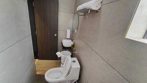 A small bathroom with a toilet, a sink, and a mirror. - Asopalav Lawns (Veraval)