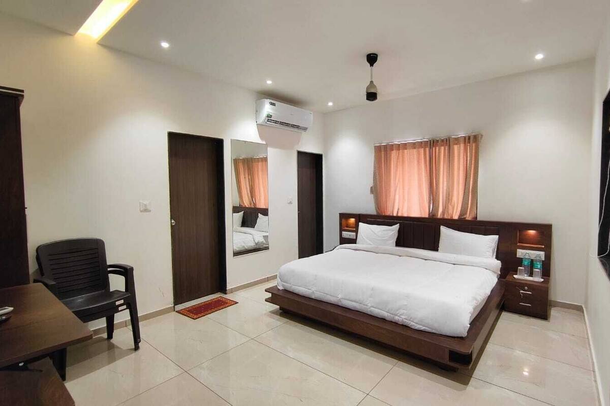 Habitación de hotel con cama, escritorio, silla, televisor, armario y equipo de aire acondicionado.