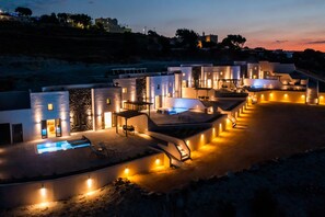 A modern resort with multiple connected buildings, outdoor swimming pools, and a well-lit patio area. - Lavadoze Luxury Suites - Adults only (Santorini)