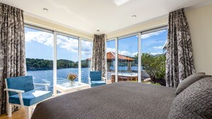 A bedroom with a large bed, a view of a lake, and a balcony with a table and chairs. - Villa Key private sea access and great views of the Adriatic sea (Zaton)