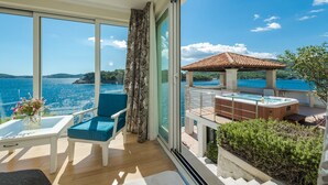 A balcony with a hot tub, a chair, and a table with flowers. - Villa Key private sea access and great views of the Adriatic sea (Zaton)