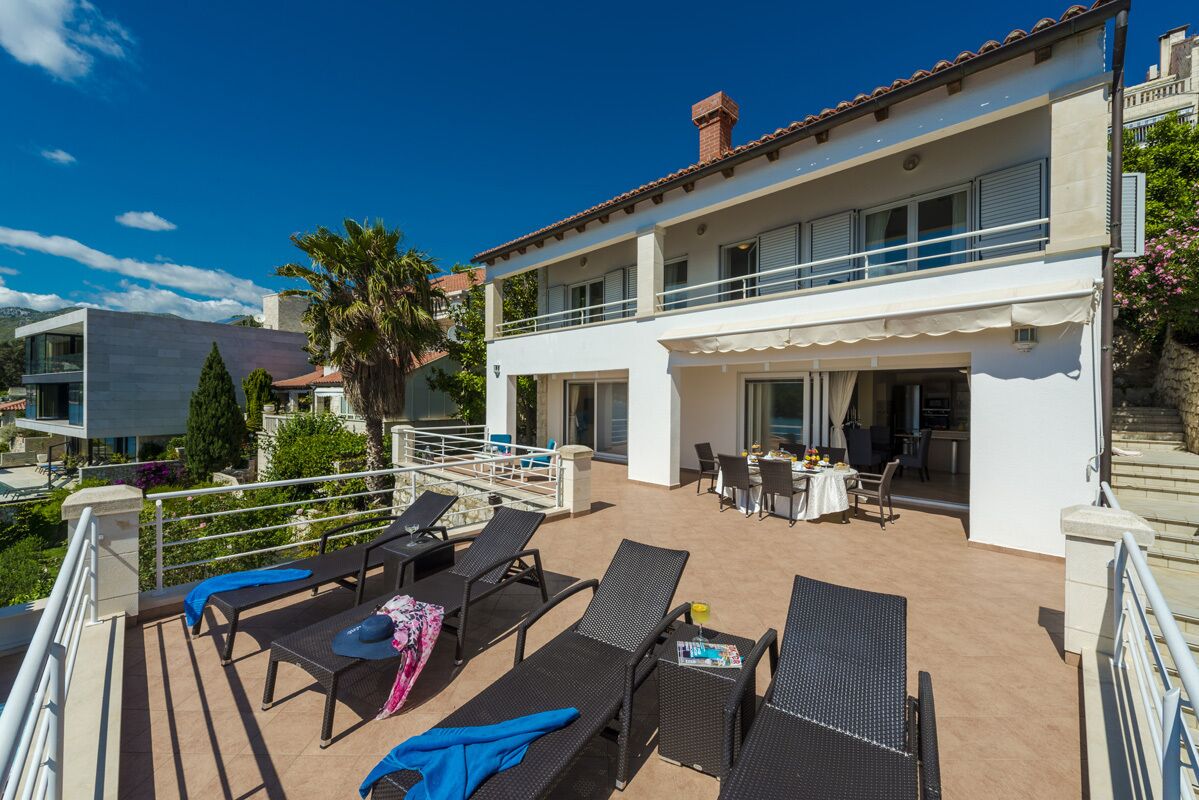 Un bâtiment à deux étages doté d’un balcon, d’un espace extérieur aménagé pour s’asseoir et d’une table à manger.