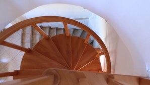 A wooden spiral staircase with a white interior and a tiled floor. - Dimokritos Apartment Pitsidia (Pitsidia)