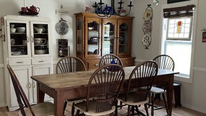 A dining area with a wooden table and chairs, a wooden cabinet with glass doors, and a chandelier.