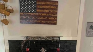 A fireplace with a star decoration, a wooden American flag above it, and a rustic stone wall.