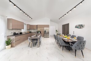 A modern kitchen with built-in appliances, a dining area with a marble floor, and a large window.