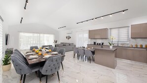 Une cuisine moderne dotée d’un îlot central, un coin repas avec une table en marbre et un espace de vie comprenant un canapé et des fauteuils.