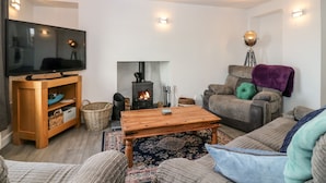 A cozy living room with a fireplace, a television, and comfortable seating. - Dolphin Cottage (Banff)