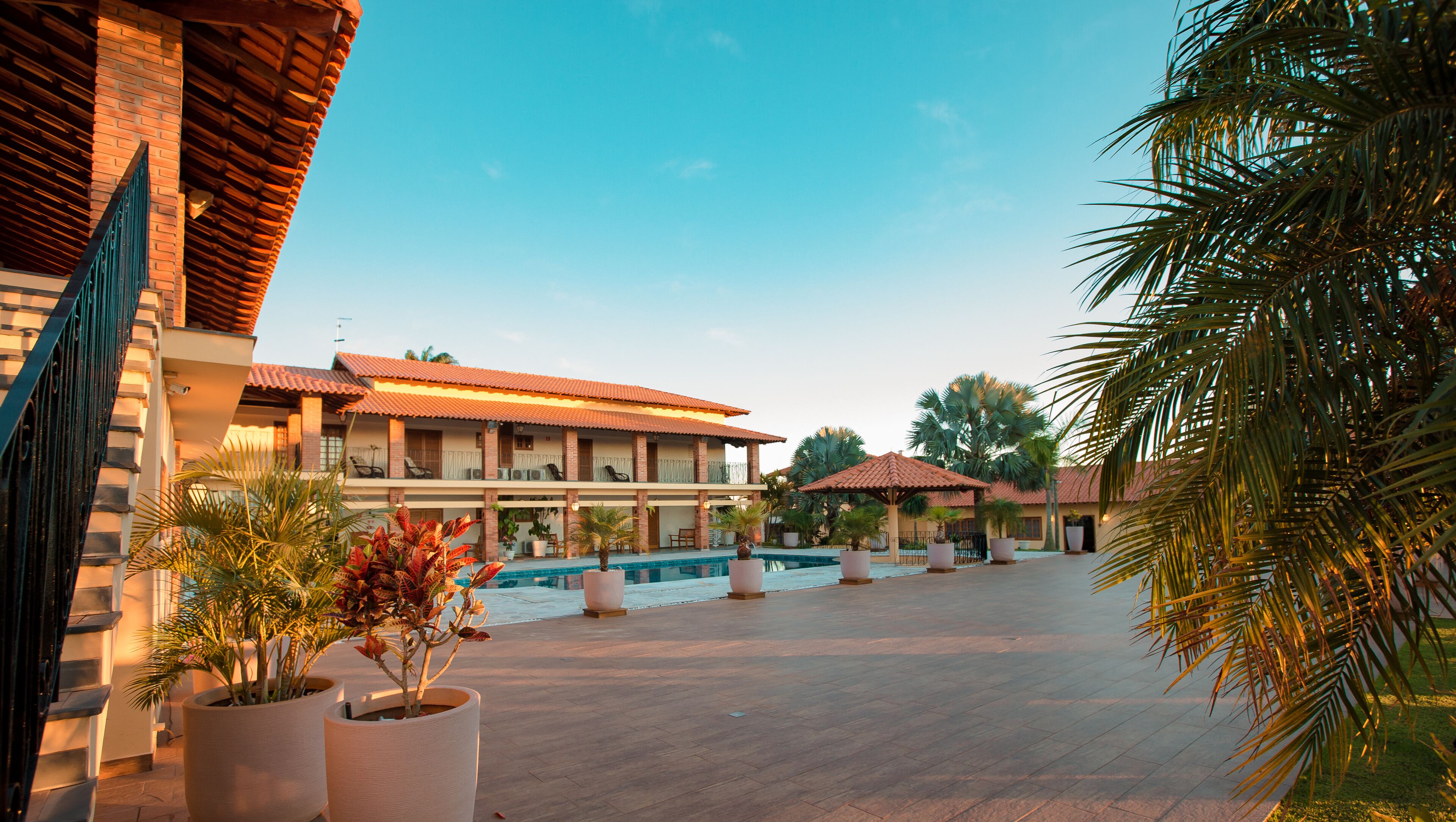 A hotel with a swimming pool, multiple balconies, and palm trees.