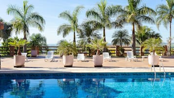 Una piscina al aire libre, sombrillas, sillones reclinables de piscina