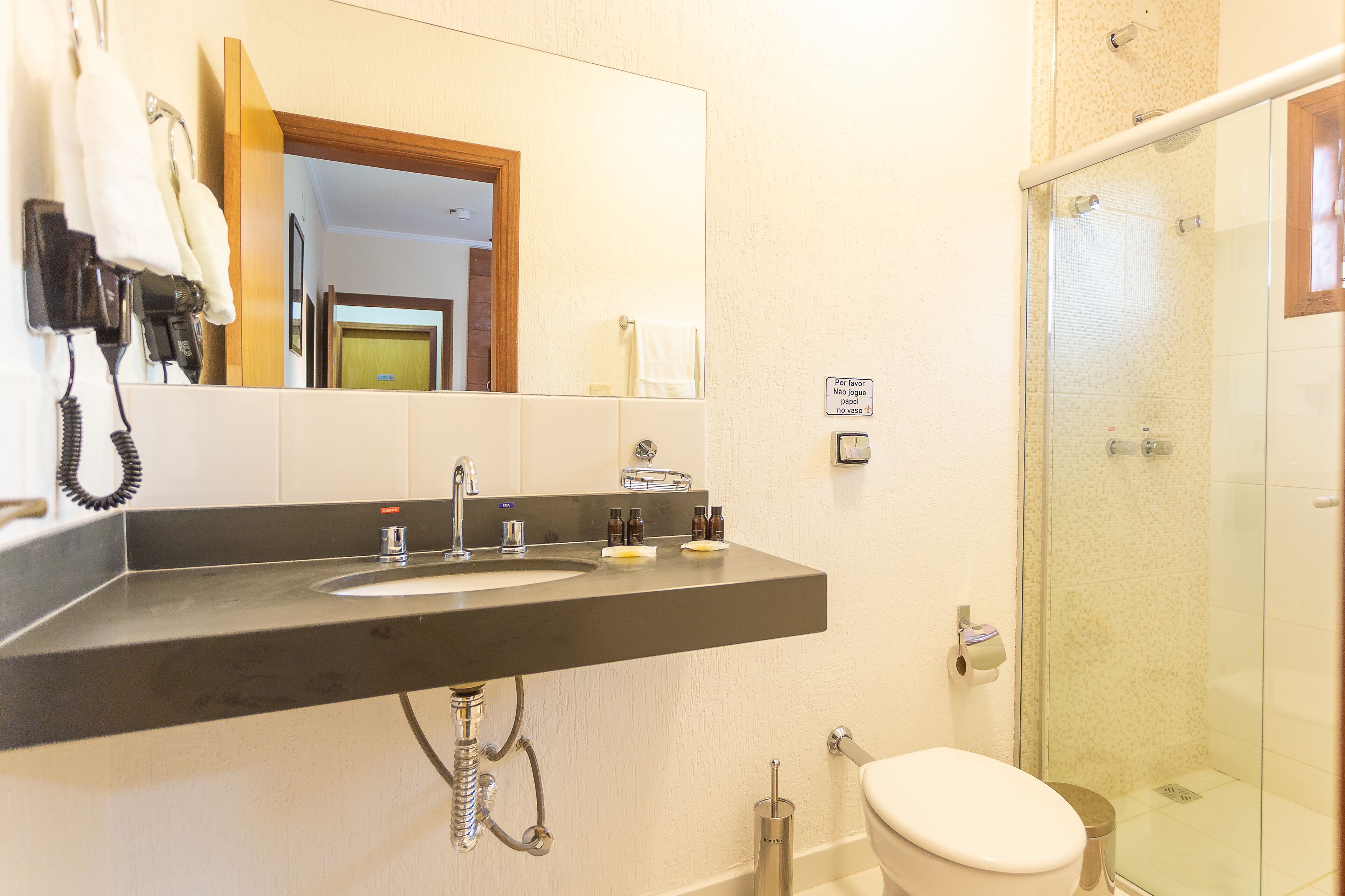 A bathroom with a double sink, a toilet, and a glass-enclosed shower.