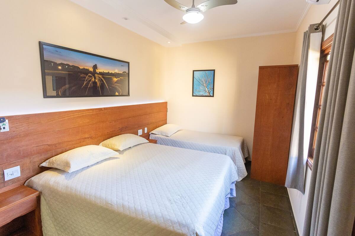 Ein Hotelzimmer mit zwei Betten, einem Holzkopfteil, einem Deckenventilator und einem Nachttisch.