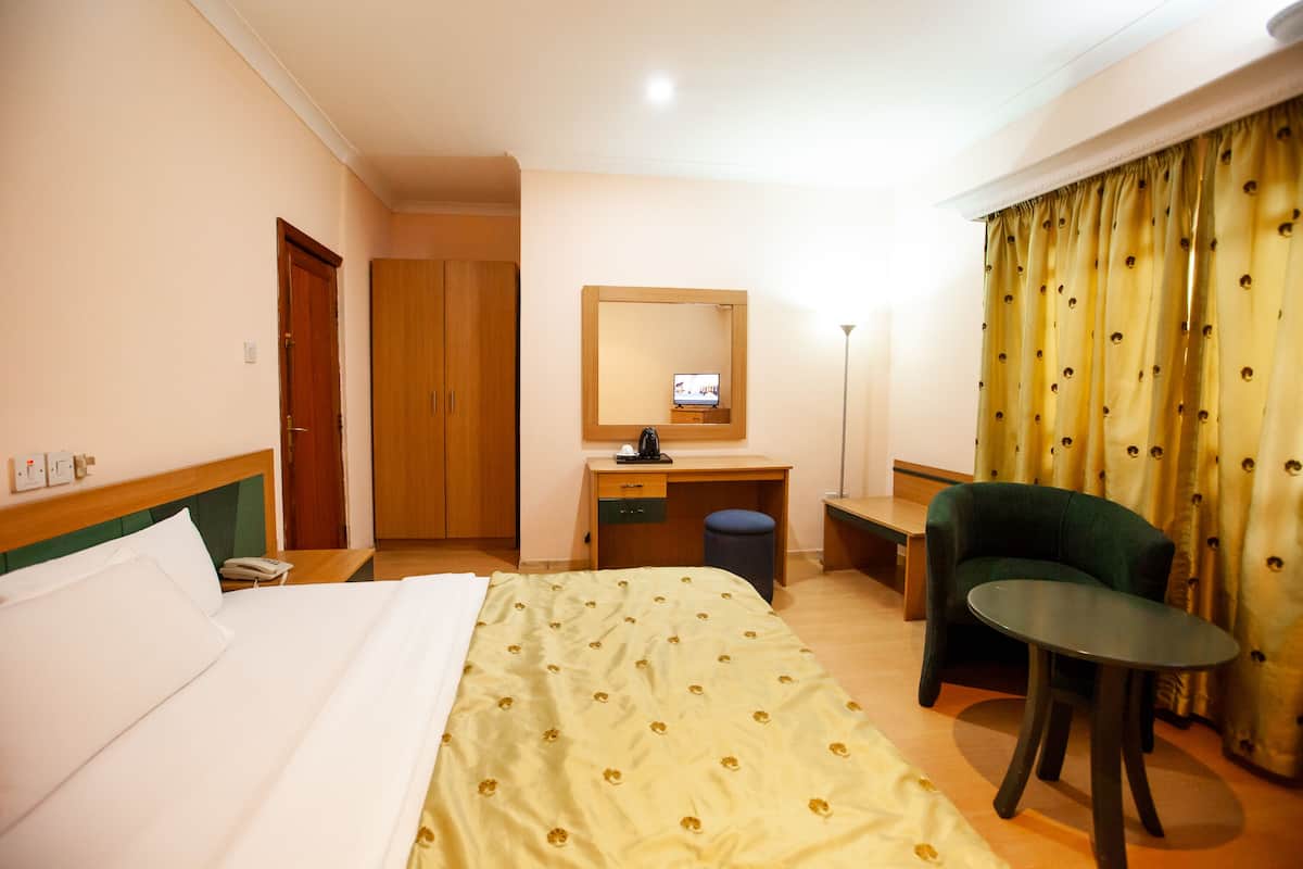 Habitación de hotel con cama, escritorio, silla y una mesita.