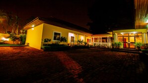 A hotel with a paved courtyard, a covered outdoor seating area, and potted plants. - GENESIS COTTAGE (Port Harcourt)
