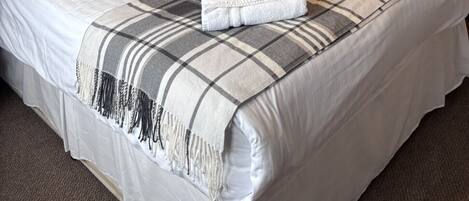 Una habitación de hotel con una cama grande, una litera, un cuadro en la pared y una lámpara.
