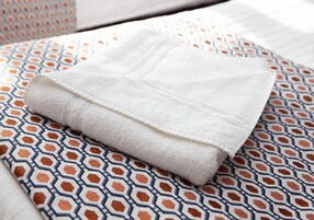 A neatly folded white towel on a patterned bedspread.