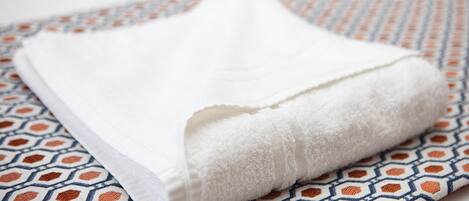 A folded white towel on a patterned fabric.