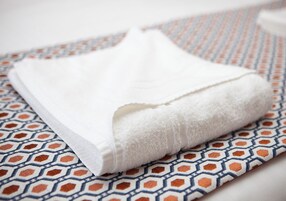 A folded white towel on a patterned fabric.