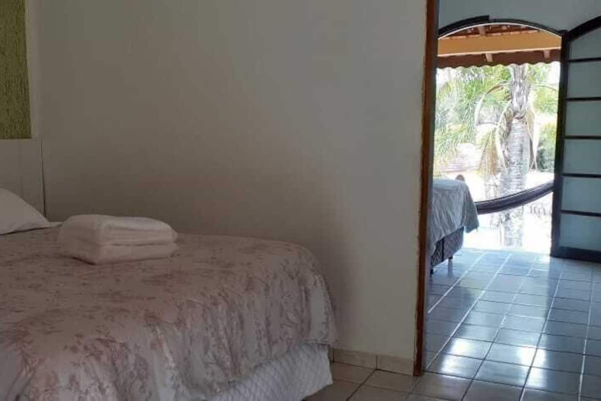 Een slaapkamer met een bed, kussens en een keurig opgevouwen handdoek.