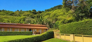 A building with a red-tiled roof, surrounded by well-maintained green hedges and a yellow fence.