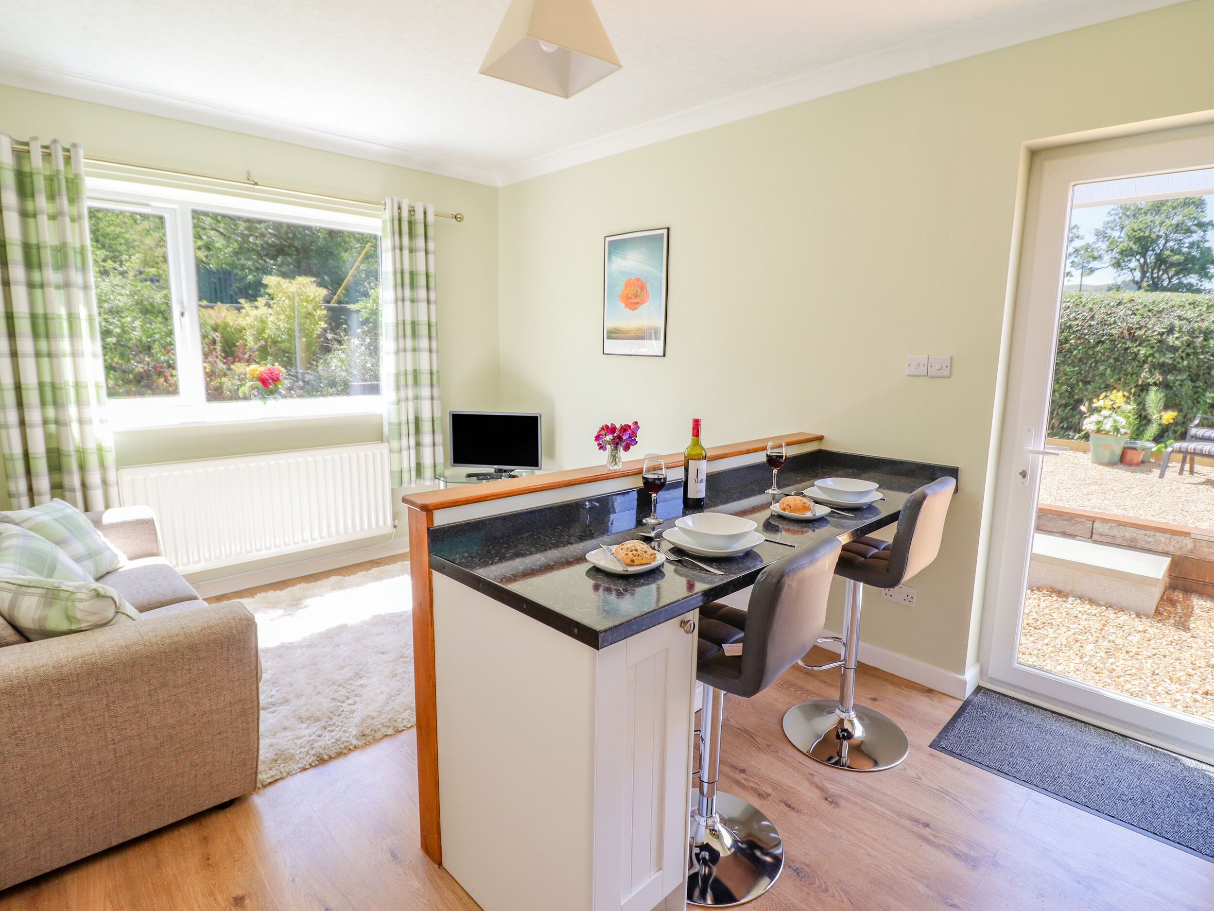 Een moderne keuken met een centraal eiland, barkrukken en een eettafel gedekt voor twee personen.