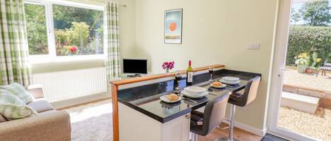Een moderne keuken met een centraal eiland, barkrukken en een eettafel gedekt voor twee personen.