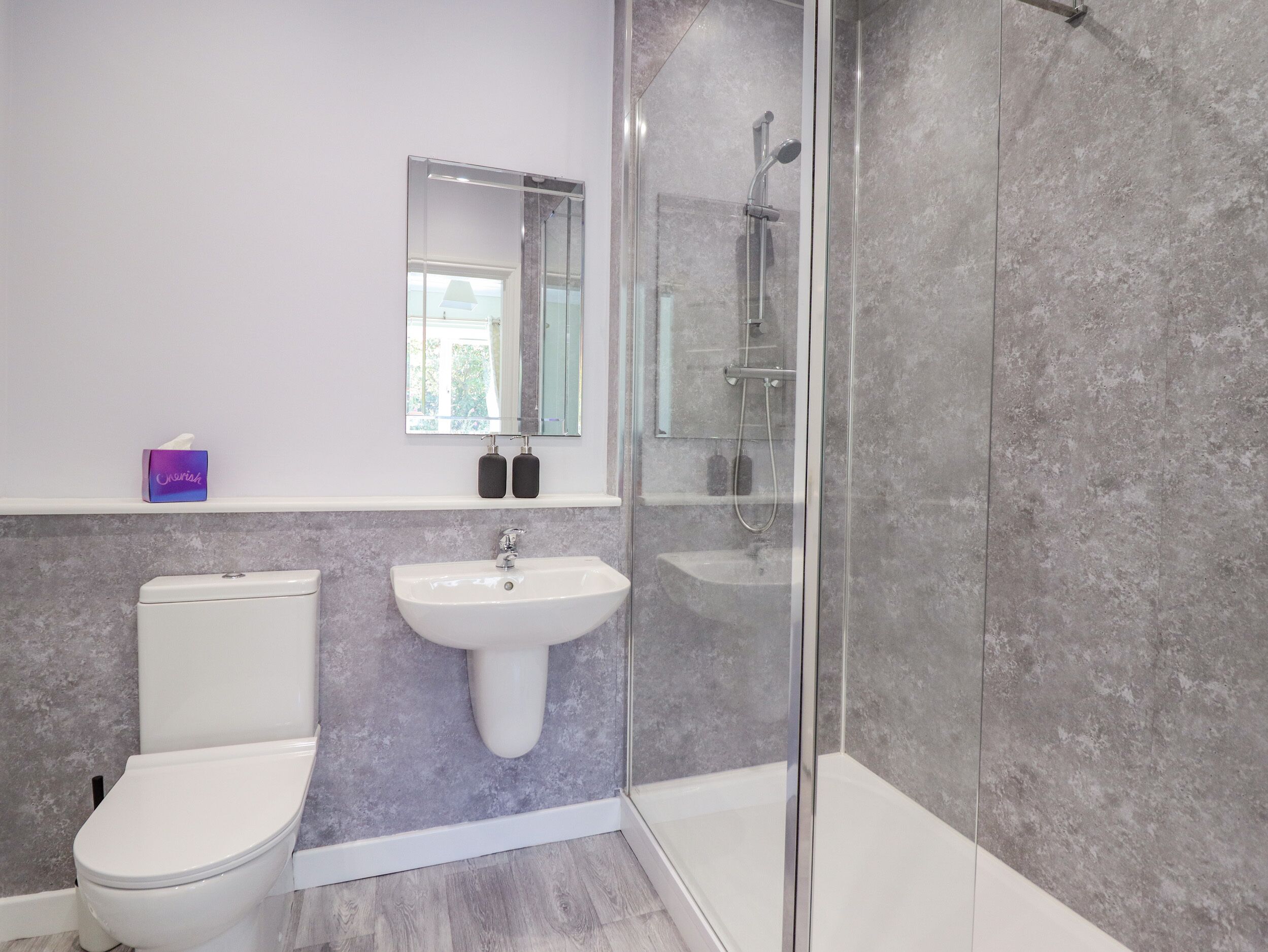 Een badkamer met toilet, wastafel en douchecabine.