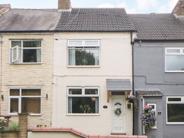 A row of terraced houses with distinct front doors, windows, and a small garden area.