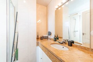 A bathroom with a marble countertop, a sink, a mirror, and a shower. - Rooftop Pied-à-terre private Sauna & Jacuzzi by BentoBox. (LISBON)