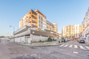 A multi-story residential building with a parking garage, a pedestrian crossing, and a clear sky. - Rooftop Pied-à-terre private Sauna & Jacuzzi by BentoBox. (LISBON)
