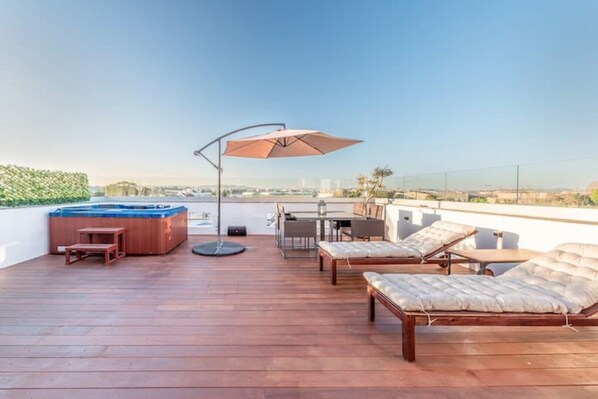 A rooftop terrace with a hot tub, lounge chairs, a table, and a large umbrella. - Rooftop Pied-à-terre private Sauna & Jacuzzi by BentoBox. (LISBON)