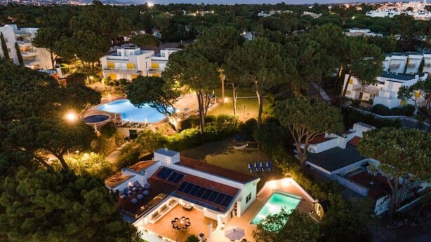 An aerial view of a residential area with modern houses, a swimming pool, and solar panels. - Bento Box Vintage Family Villa & Hot Pool (Vilamoura)