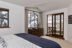 Enjoy a restful stay in this cozy room with a large bed, dresser, and balcony offering a view of snow-covered trees.