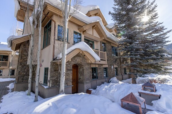 Stunning two-story lodge with a balcony and multiple windows, set amidst a serene winter wonderland.