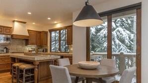 A kitchen with wooden cabinets, a granite countertop, and a large island with stools. - JUST LISTED! Stylish townhome in West Ketchum -- private hot tub, close to bike path, river, ski lifts! (Ketchum)