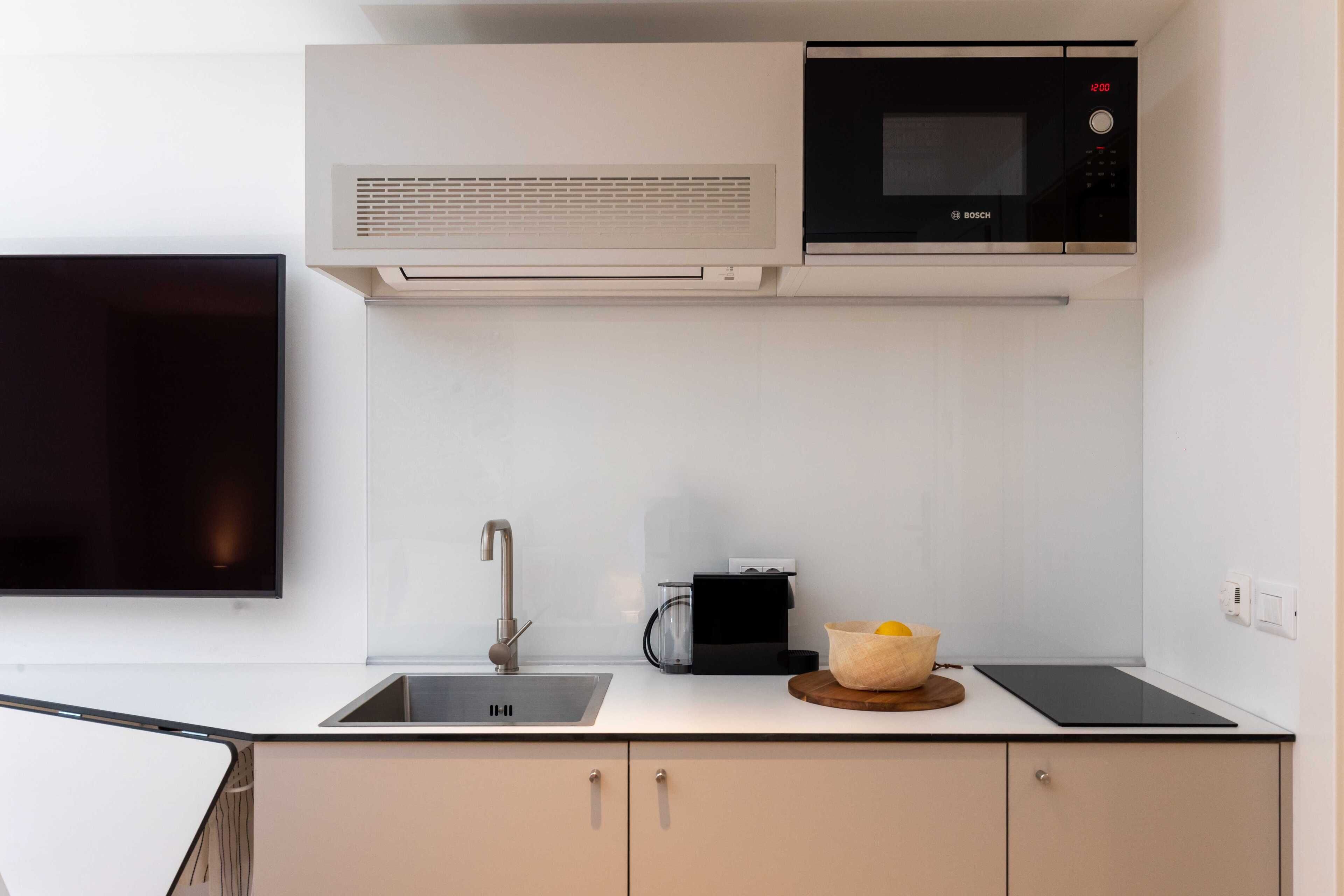A modern kitchen with a Bosch microwave, a coffee maker, and a sink.