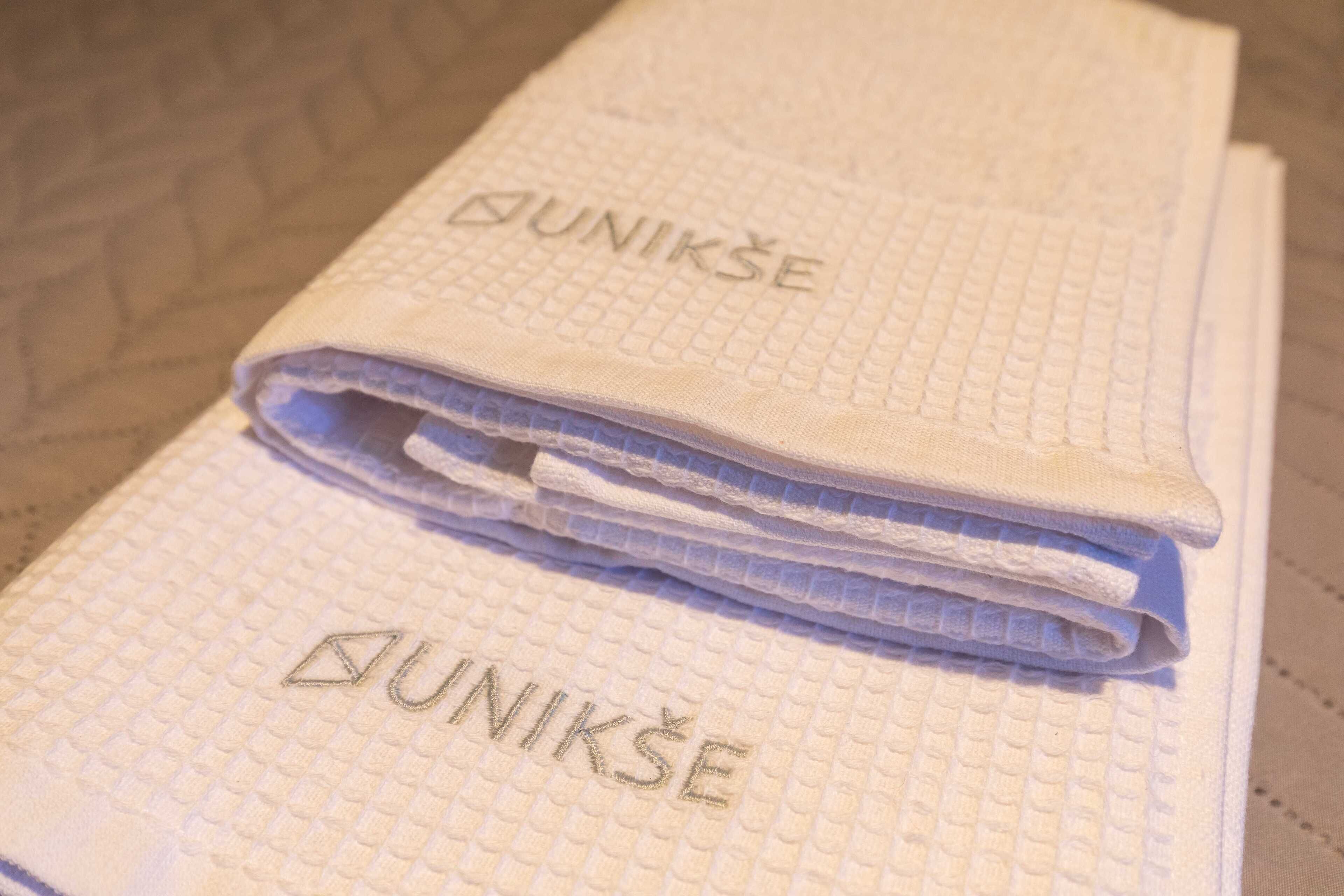 Un montón de toallas dobladas con el nombre de la marca “DUNIKŠE” bordado.