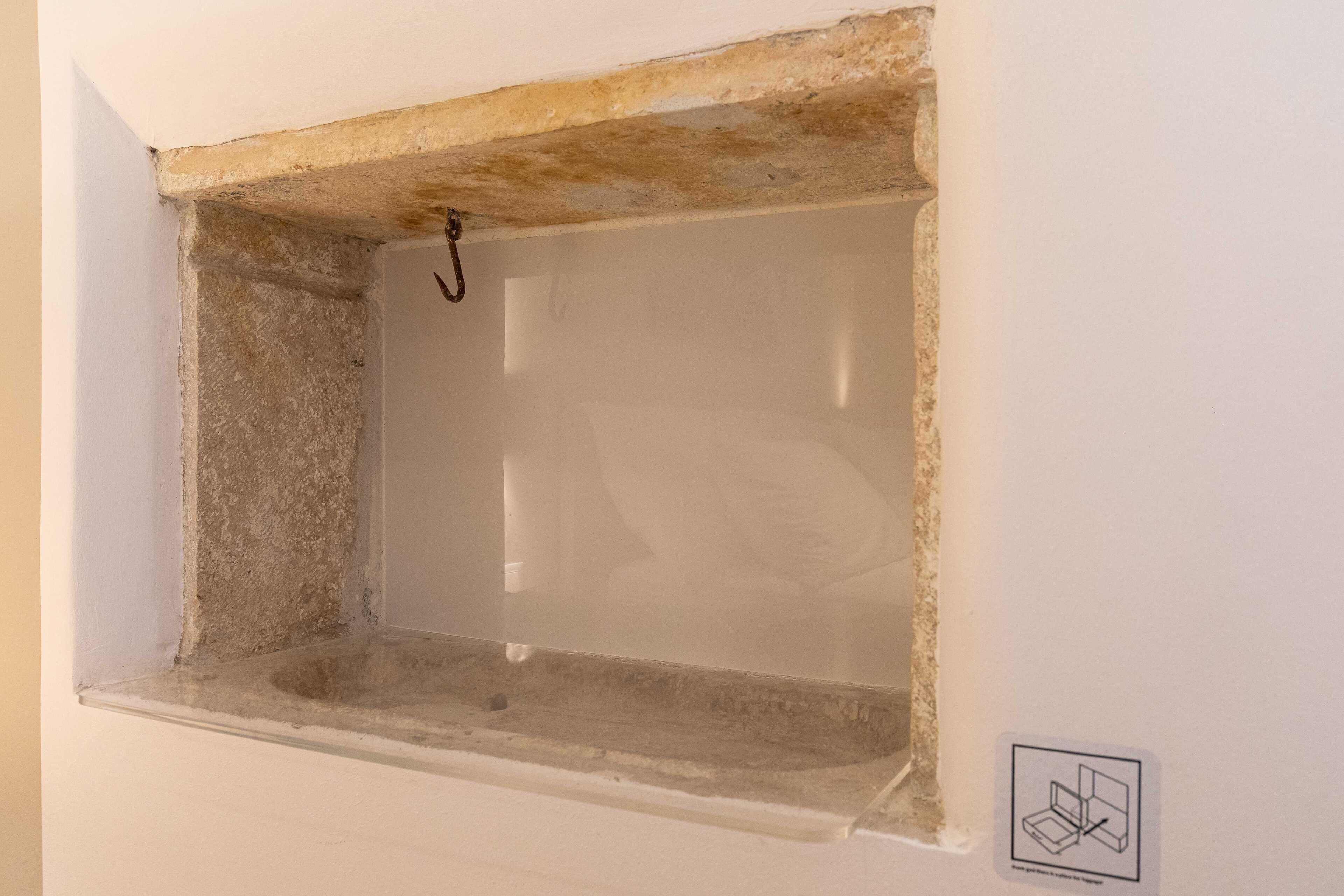 A small, empty window with a concrete ledge and a hook.