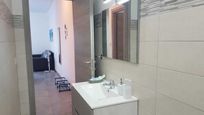Uma casa de banho moderna com uma sanita branca, um espelho e um porta-toalhas.