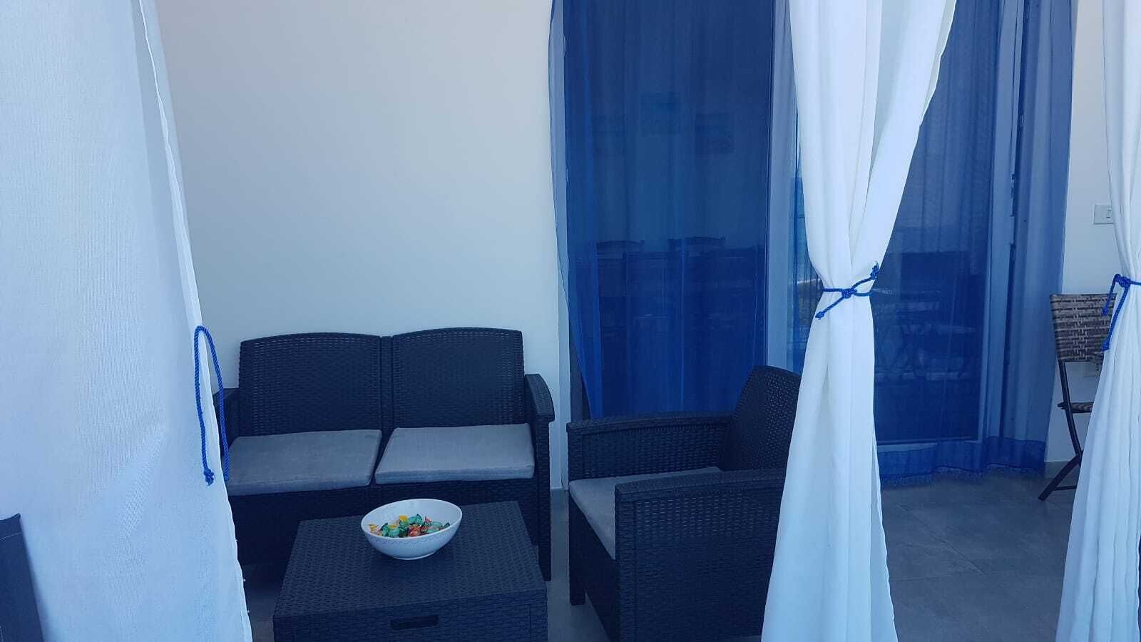 A balcony with a sofa, a small table, and a bowl of fruit.