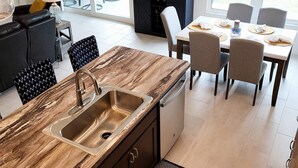 A modern kitchen with a wooden countertop, a sink, and a dining area with chairs and a table. - 3/2 IN THE VILLAGE OF ST. CATHERINE GAS GOLF CART, CLOSE TO SAWGRASS GROVE (Wildwood)