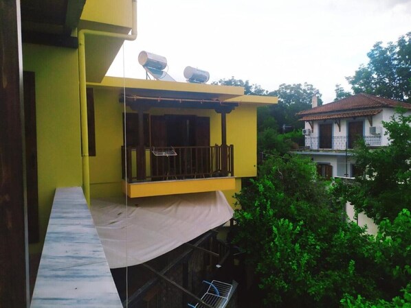 Een geel gebouw met een balkon en een overdekt terras.