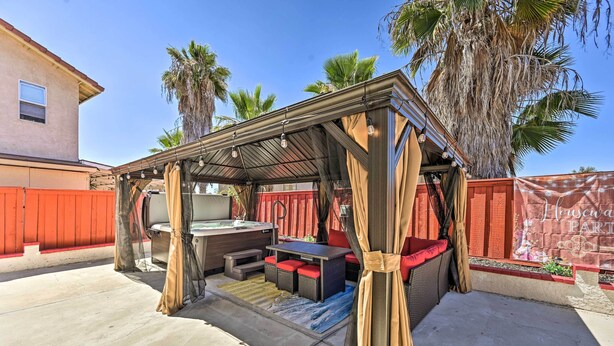 Un patio techado con una parrilla, zona de estar y vistas al jardín trasero.