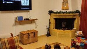 Un salon comprenant un canapé, une table basse, une cheminée et un téléviseur fixé au mur.