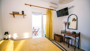 Une chambre à coucher avec un lit, un bureau, une chaise, une télévision et une fenêtre avec des rideaux.