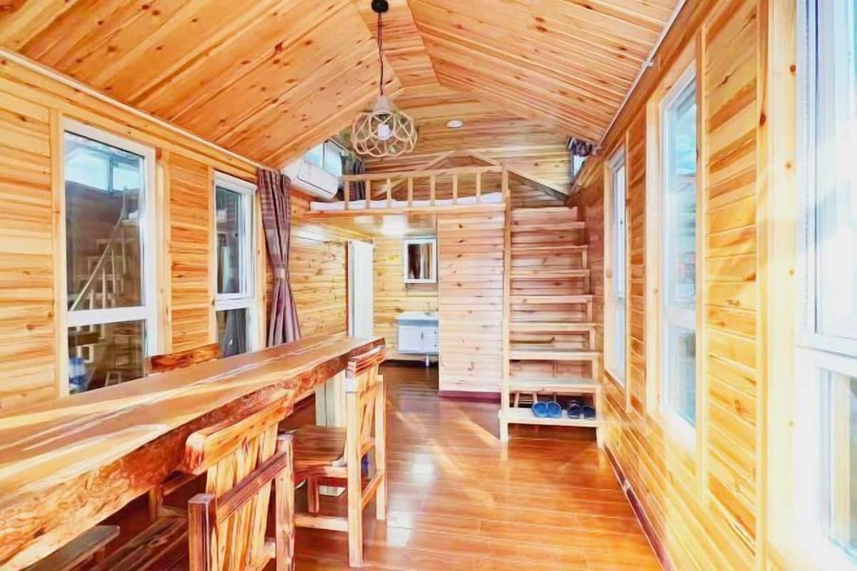 L’intérieur d’une cabane en bois comprend un coin repas, un escalier et une mezzanine.