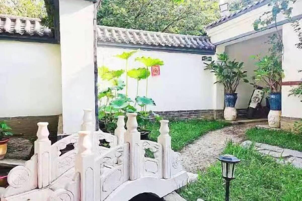 Une cour agrémentée d’un pont en pierre décoratif, de plantes en pot et d’un sentier.