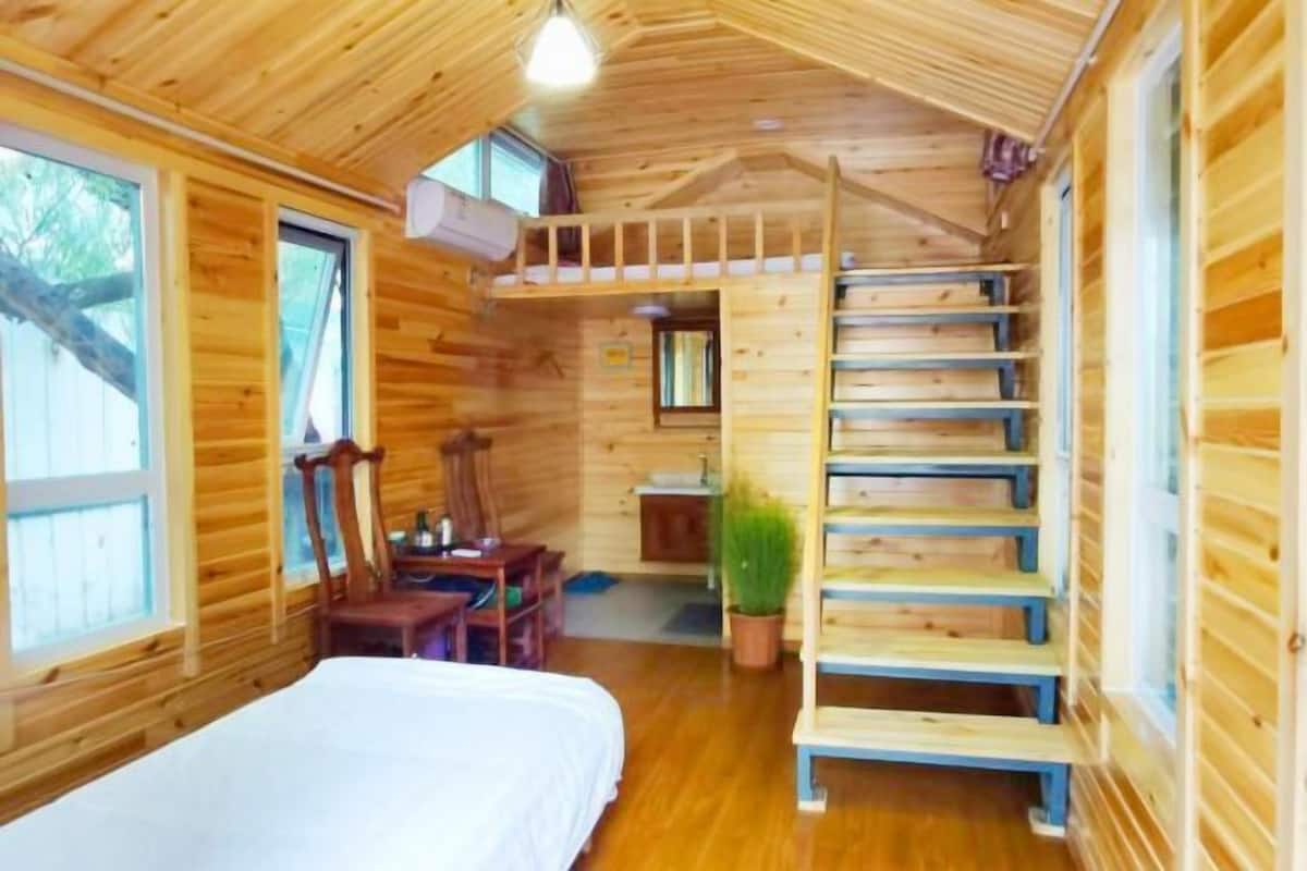 Une cabane en bois avec un lit superposé, un bureau et un escalier.